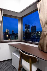 a room with a desk and a window with a view at Shinbashi Urban Hotel in Tokyo