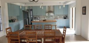 uma cozinha com armários azuis e uma mesa e cadeiras em Modern spacious home in heart of Cape Winelands em Somerset West
