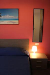 マリーナ・ディ・ラグーザにあるLa Casa Biancaのベッドルーム(ベッド1台、鏡、ランプ付)