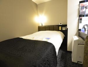 APA Hotel Kamataeki-Higashi في طوكيو: غرفة فندق فيها سرير واضاءة على الحائط