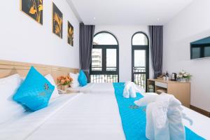 a bedroom with a large white bed with blue pillows at Euro Star Riverside Hotel in Danang