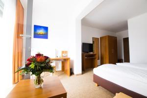 ein Hotelzimmer mit einer Blumenvase auf dem Tisch in der Unterkunft Hotel Darstein in Mannheim