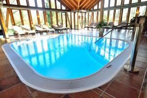 a large swimming pool in a building with chairs at Schlosshotel Weyberhöfe in Hösbach