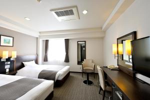 a hotel room with two beds and a desk at Saijo Urban Hotel in Saijo