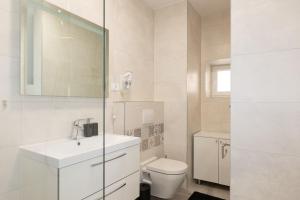 a white bathroom with a toilet and a sink at Apinelo in Supetar