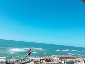 a view of the ocean from a beach with a flag at Royal Crown Hotel عائلات فقط in Alexandria