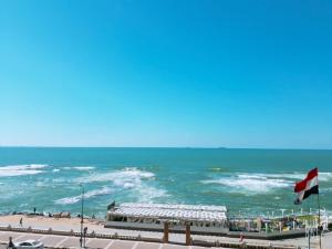 a view of a beach with a flag and the ocean at Royal Crown Hotel عائلات فقط in Alexandria