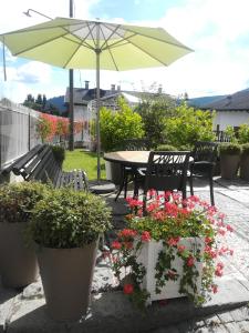 a patio with a table and umbrella and flowers at La Stella delle Alpi in Vico Canavese