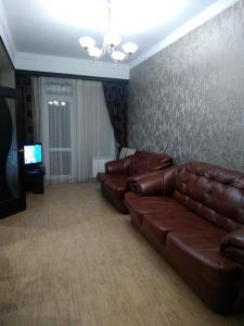 a living room with a brown leather couch and a television at Apartment Vershyna 401 in Dombay