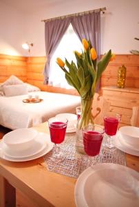 una mesa con platos y vasos y un jarrón con flores en Willa Przy Skoczni, en Zakopane