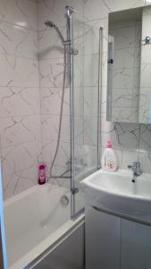 een witte badkamer met een douche en een wastafel bij Bright apartment on top in Panevėžys