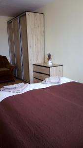 a large bed with a red blanket and a cabinet at Bright apartment on top in Panevėžys