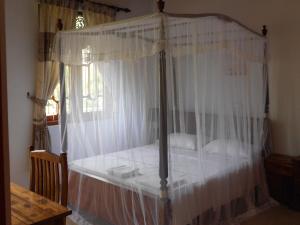 Un dormitorio con una cama con dosel y cortinas blancas. en Accoma Villa, en Hikkaduwa