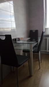 una mesa de cristal y 2 sillas negras en una habitación en Bright apartment on top en Panevėžys