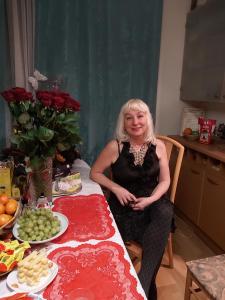 Eine ältere Frau, die an einem Tisch mit Essen sitzt. in der Unterkunft VGH accommodation services in Vilnius