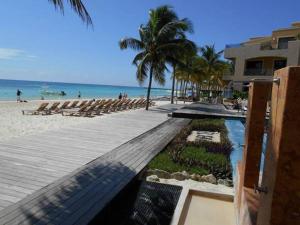 una playa con sillas y el océano y un edificio en El Faro 304 Coral Penthouse, en Playa del Carmen