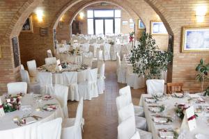 uma sala cheia de mesas e cadeiras brancas com uma mesa branca em Masseria Casacapanna em Chieuti