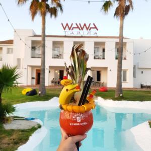 a person holding a drink in front of a pool at Wawa Tarifa in Tarifa