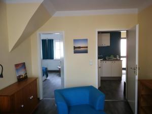 a living room with a blue chair and a kitchen at Ferienwohnung Nunatak am Plöner See in Dersau