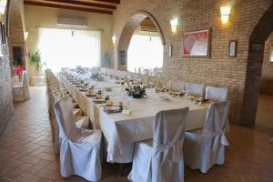 uma mesa longa com mesas brancas e cadeiras num quarto em Masseria Casacapanna em Chieuti