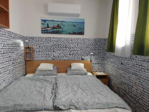 1 dormitorio con 1 cama grande en una pared de ladrillo en Kid Família Panzió Balatonszárszó, en Balatonszárszó