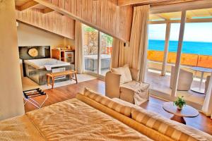 a living room with a couch and a large window at Litohoro Olympus Resort Villas & Spa in Plaka Litochorou