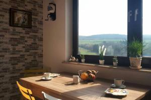 a wooden table with chairs and a window with plants at Ferienwohnung Alpaka Blick in Schneppenbach