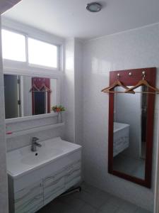 a white bathroom with a sink and a mirror at Z.H.P Hotel in Ban Khlong Nung