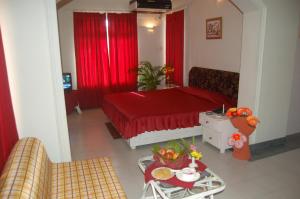 a living room with a red bed and a table at Toshali Sands Puri in Puri