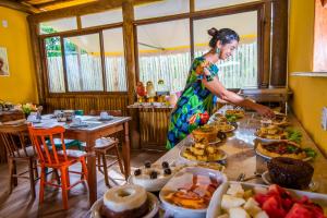 uma mulher a preparar um buffet de comida num restaurante em Pousada Tropicarim em Itacimirim