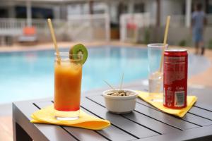 una copa y una lata en una mesa junto a una piscina en Hôtel Saint-Georges, en Saint-Claude