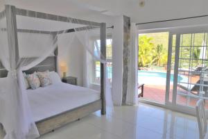 a bedroom with a canopy bed and a swimming pool at Marigot Palms Luxury Caribbean Apartment Suites in Marigot Bay