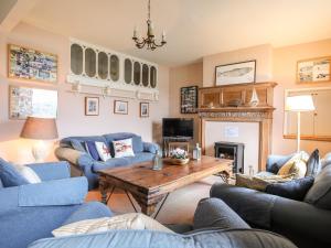 a living room with blue couches and a wooden table at Tan Y Coed in Menai Bridge