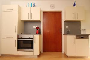 una cucina con armadi bianchi e una porta marrone di HH-Apartments a Scheifling