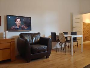 a living room with a chair and a tv on the wall at Apartament Wybickiego in Poznań