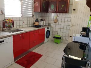 a kitchen with red cabinets and a washing machine at La maison aux Orchidées in Petit-Bourg +33 photos
