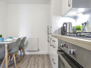 a kitchen with a table and chairs in a room at Tudors eSuites 7 Single Beds Driveway & Garden in Birmingham