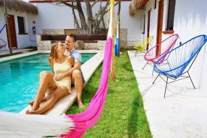科苏梅尔Kinta Kan Hotel Cozumel的坐在游泳池旁吊床上的男女
