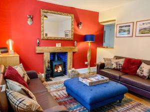 een woonkamer met rode muren en een open haard bij Happy Feet Cottage in Bradwell