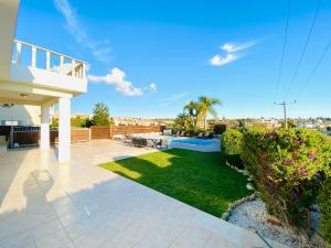 een achtertuin met een patio en een tuin met groen gras bij Acropolis Villa 8 in Klorakas