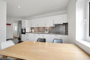a kitchen with white cabinets and a wooden table and chairs at Just Sleep in Esbjerg
