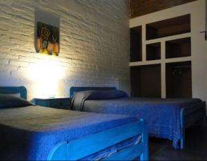 1 dormitorio con 2 camas y pared de ladrillo en Posada Argimon en San Marcos Sierras