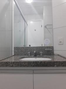 eine Badezimmertheke mit einem Waschbecken und einem Spiegel in der Unterkunft Flat Golden Fortaleza in Fortaleza