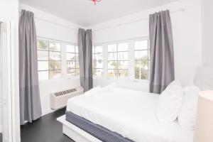 a white bedroom with a bed and windows at The Donovan at Miami Beach in Miami Beach