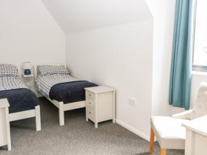 um quarto com duas camas, uma mesa e uma cadeira em Tricker's Cottage em Attlebridge