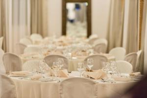 a room with white tables and chairs with wine glasses at Villa del Parco Resort in San Baronto