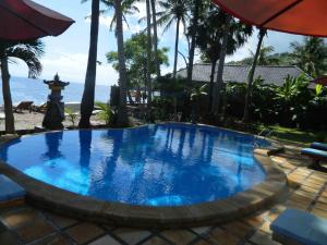 a large blue swimming pool next to the beach at Bali Bhuana Beach Cottages in Amed