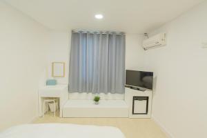 um quarto branco com uma cama e uma televisão em James Blue Hostel em Sokcho