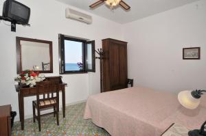 a bedroom with a bed and a table and a mirror at Hotel Villaggio Stromboli - isola di Stromboli in Stromboli