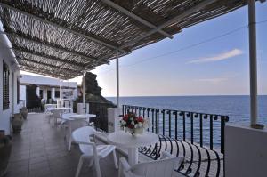 a row of tables and chairs on a balcony with the ocean at Hotel Villaggio Stromboli - isola di Stromboli in Stromboli